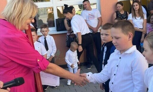 Nauczycielka podaje rękę nowemu uczniowi.